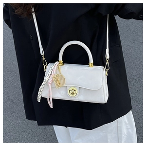 Détail du sac en cuir verni blanc avec fermoir tournant doré et foulard en soie