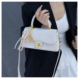 Détail du sac en cuir verni blanc perle avec fermoir doré et pendentif de tennis chic