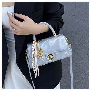 Détail d'un sac à main gris marbré avec finitions dorées et breloque raquette de tennis