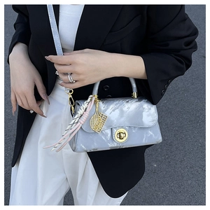 Détail du sac bandoulière gris clair à motif marbre avec fermoir doré et pompon décoratif