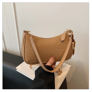 Detail of crocodile embossed underarm bag with wooden beads and golden chain strap
