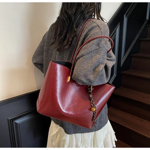 Detail of dark red vintage tote bag showing glossy leather texture and gold hardware