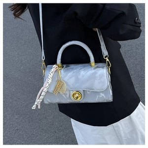 Détail du sac à main gris marbré avec fermoir doré et décoration de foulard