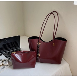 Detail of burgundy leather tote set including an inner zipper pouch on a white desk