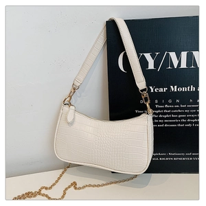 Detail of crocodile pattern faux leather baguette bag with gold chain and strap