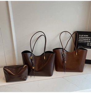 Detailed view of deep brown leather tote set with gold ball charm and woven texture