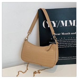 Detail of light khaki baguette bag featuring crocodile texture and gold chain strap