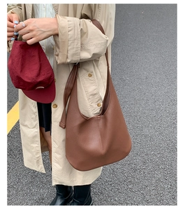 Detail einer braunen Hobo-Tasche aus Leder mit Lychee-Struktur und breitem Gurt