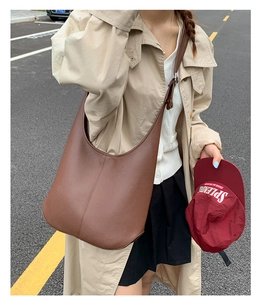 Braune Hobo-Tasche mit Litschimuster und breitem Schultergurt in modischer Umgebung