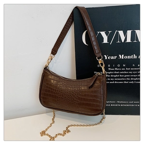 Detail of dark brown faux crocodile leather underarm bag with gold chain strap
