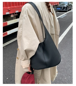 Detailansicht der großen schwarzen Hobo-Tasche aus strukturiertem Leder beim Tragen