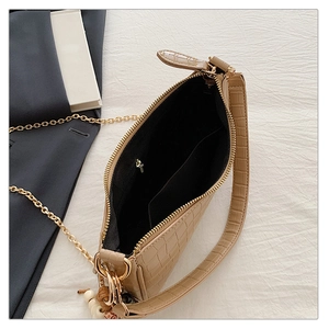 Detail view of khaki crocodile pattern handbag with gold hardware and interior capacity