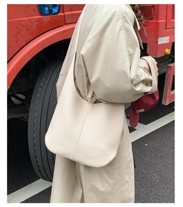 Detail der beigen Tragetasche aus genarbtem Leder, getragen von einem Model im Freien