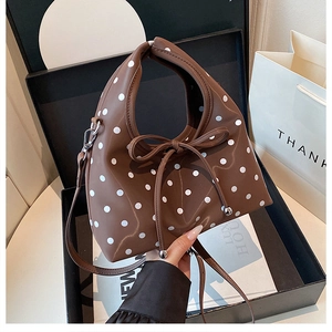 Détail du sac marron à pois avec nœud en cuir et billes métalliques en coffret cadeau