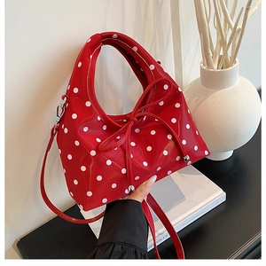 Détail d'un sac à pois rouges avec nœud coulissant et finitions de perles argentées fines
