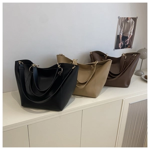 Sacs cabas minimalistes en noir, beige et moka avec anneaux métalliques sur étagère blanche