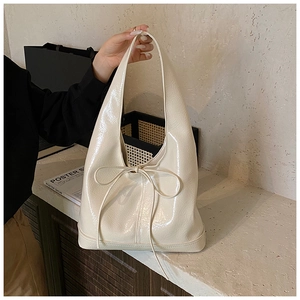 Detail of hobo bag with glossy cream leather texture and delicate ribbon bow accent