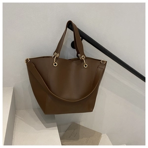 Détail d'un grand sac cabas en cuir marron foncé avec anneaux dorés et doubles poignées