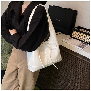 Close-up of a white textured leather shoulder bag with drawstring detail and glossy finish