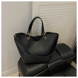 Détail d'un sac cabas en cuir noir avec anneaux dorés et double bandoulière élégante