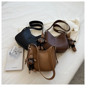 Minimalist underarm bucket bags in black, dark brown, and camel with plush rabbit charms