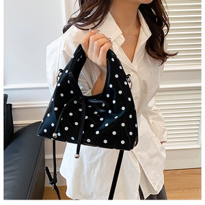Vue détaillée des grands pois blancs sur le sac à bandoulière noir brillant à cordon serrage