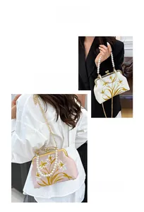Close-up of vintage embroidered floral handbag with pearl handle and gold chain detail