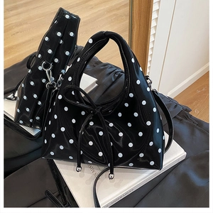 Gros plan d'un sac à main noir brillant à pois avec nœud en cuir et reflet de miroir