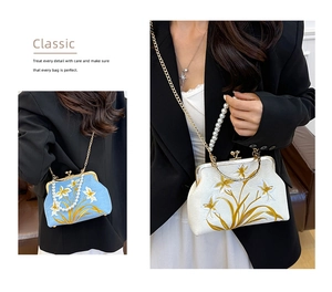 Detail of floral embroidery, pearl handle and metal chain on a vintage clasp bag