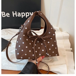 Détail d'un sac à main marron à pois avec cordon nœud papillon et finition brillante