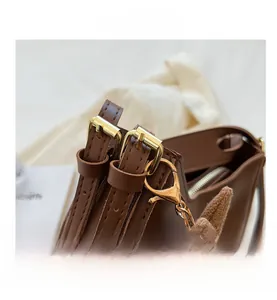 Detail of adjustable leather strap with gold buckle and a cute rabbit bag charm