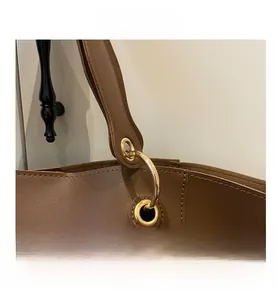 Détail du sac cabas en cuir marron avec anneaux dorés et surpiqûres de qualité