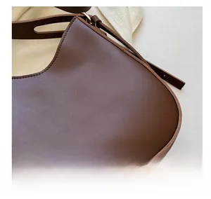 Close-up of matte dark brown leather texture and stitching on the underarm bucket bag
