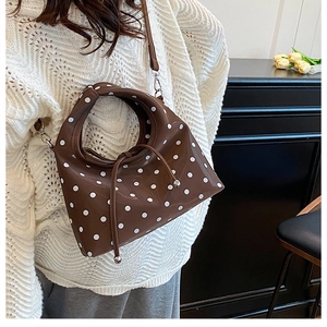 Détail du sac à bandoulière marron à pois blancs avec texture lisse brillante
