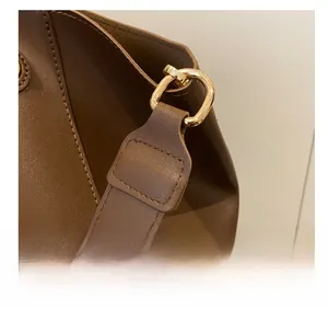 Détail de la sangle en cuir marron foncé avec boucle en D dorée et couture précise