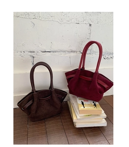 Detail of burgundy and dark brown pleated suede handbags with round sturdy handles