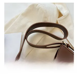 Close-up of matte brown leather shoulder strap with elegant gold metal buckle detail