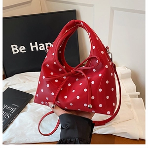 Gros plan du sac à main rouge à pois avec un nœud décoratif et des détails en métal argenté