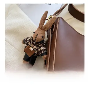 Detailed close-up of a brown knitted rabbit charm with houndstooth sweater and bag