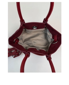 Detail view of burgundy suede handbag interior with herringbone lining and magnetic clasp