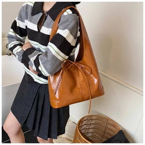 Detail of caramel glossy patent leather hobo bag with a stylish ribbon bow knot