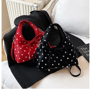 Détail des sacs à main à pois rouges et noirs avec nœuds sur un canapé blanc