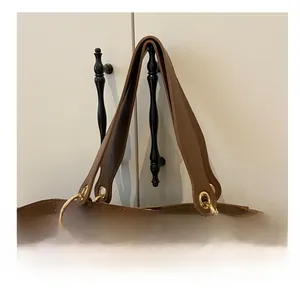Détail de la poignée en cuir marron avec boucles dorées sur le sac seau chic