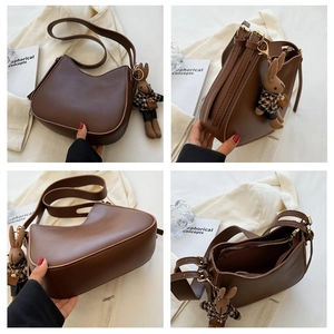 Detail view of dark brown crescent bucket bag with adjustable strap and rabbit charm