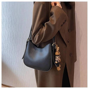 Detail of minimalist black crescent underarm bag with a stylish houndstooth bunny charm