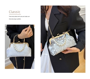 Detail of white embroidery evening bag with pearl handle and golden chain strap