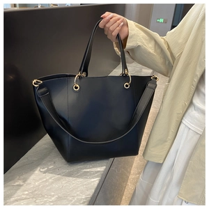 Gros plan d'un sac seau en cuir noir avec des détails dorés dans un cadre intérieur épuré