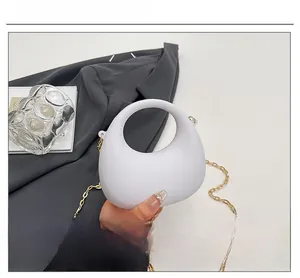 Dettaglio della borsa in acrilico bianco minimalista con finitura opaca e catena oro