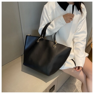 Détail d'un sac cabas en cuir noir avec d'élégants anneaux métalliques dorés arrondis