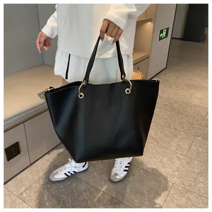 Détail d'un cabas en cuir noir avec un grand connecteur de poignée en anneau doré